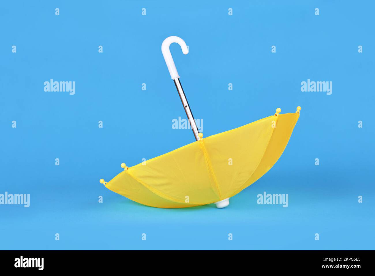 Ombrello giallo capovolto su sfondo blu Foto Stock