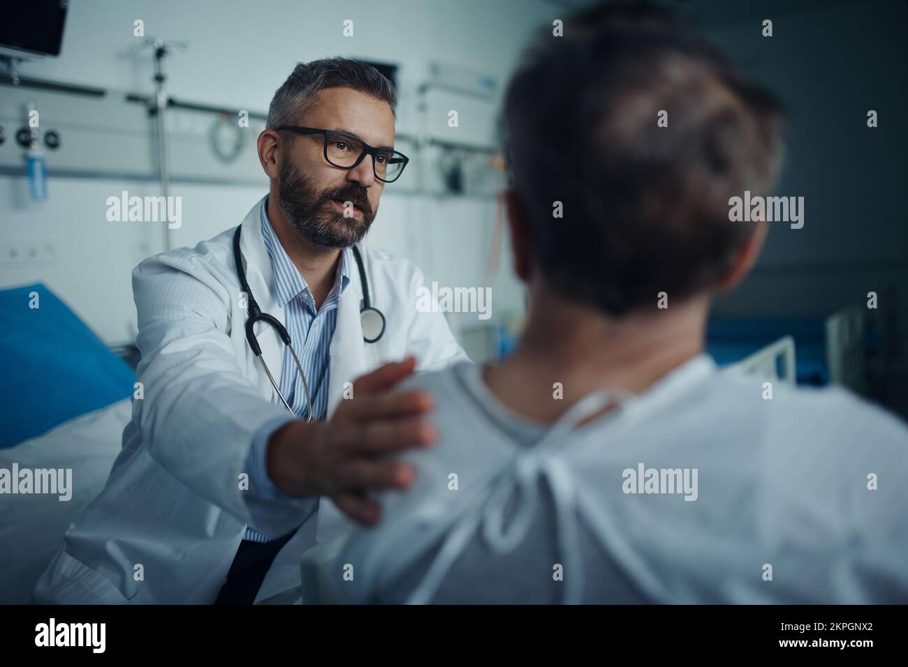 Medico maturo consolando e spiegando la diagnosi al suo paziente. Foto Stock