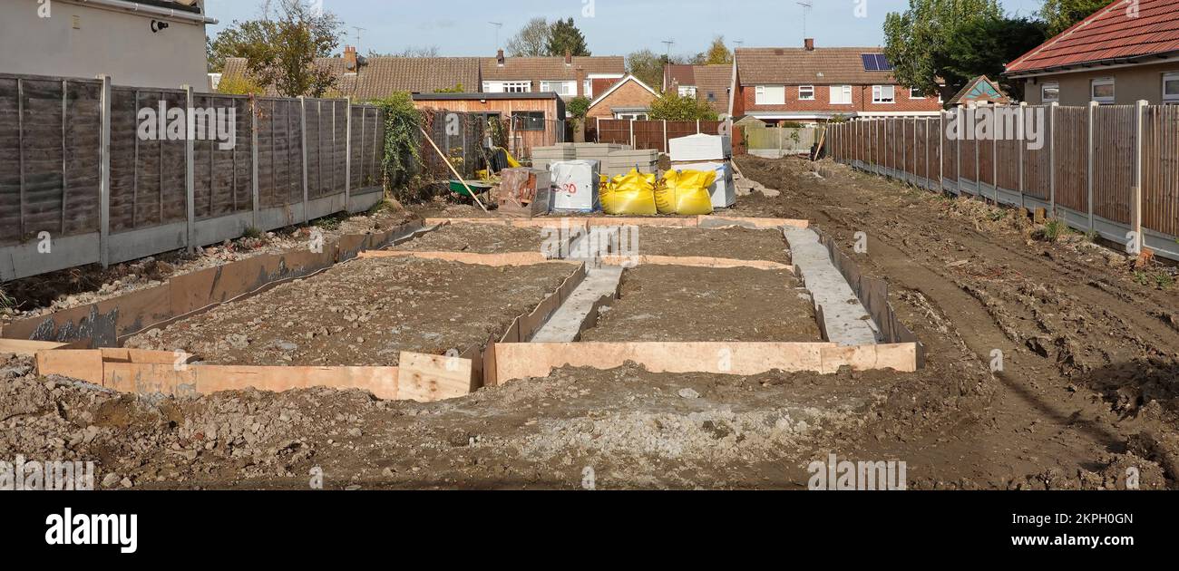 Calcestruzzo misto pronto pompato trasportato da tubo dalla strada direttamente in riempimento di trincea fondamenta di fondazione della casa indipendente Essex Inghilterra UK Foto Stock