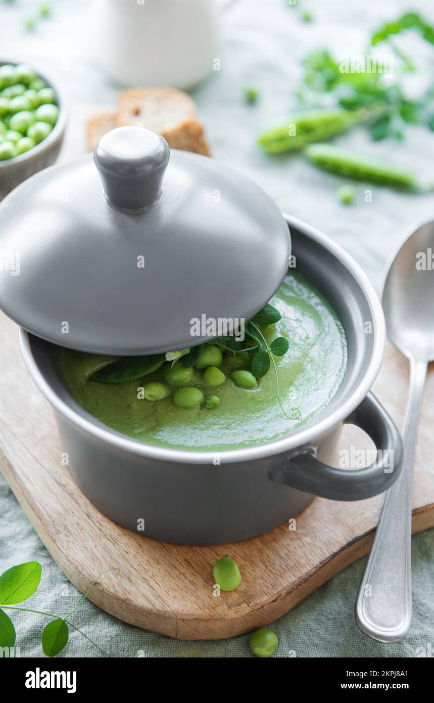 Ciotola per zuppa di piselli freschi e verdi su sfondo di cemento grigio Foto Stock