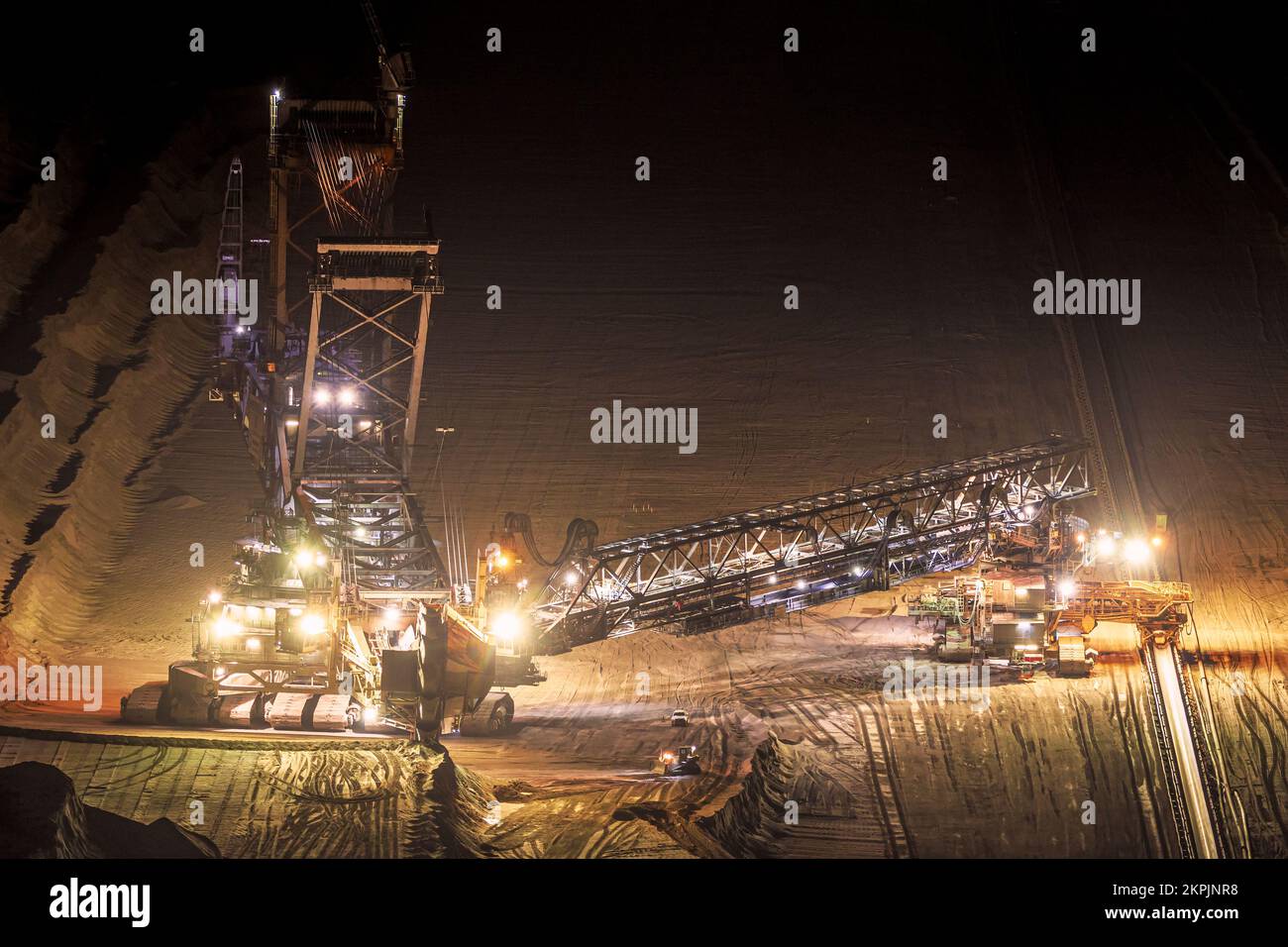 Attrezzature minerarie pesanti al lavoro in una miniera a cielo aperto al crepuscolo. Foto Stock