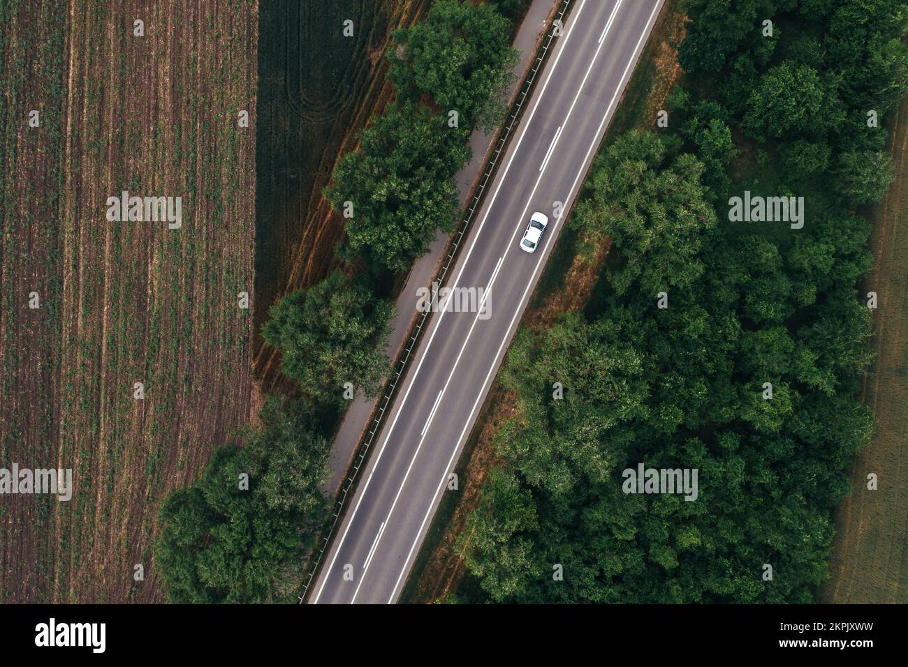 Vista dall'alto dell'autostrada asfaltata diritta attraverso il paesaggio di campagna in estate con auto che guida lungo la strada, drone pov Foto Stock