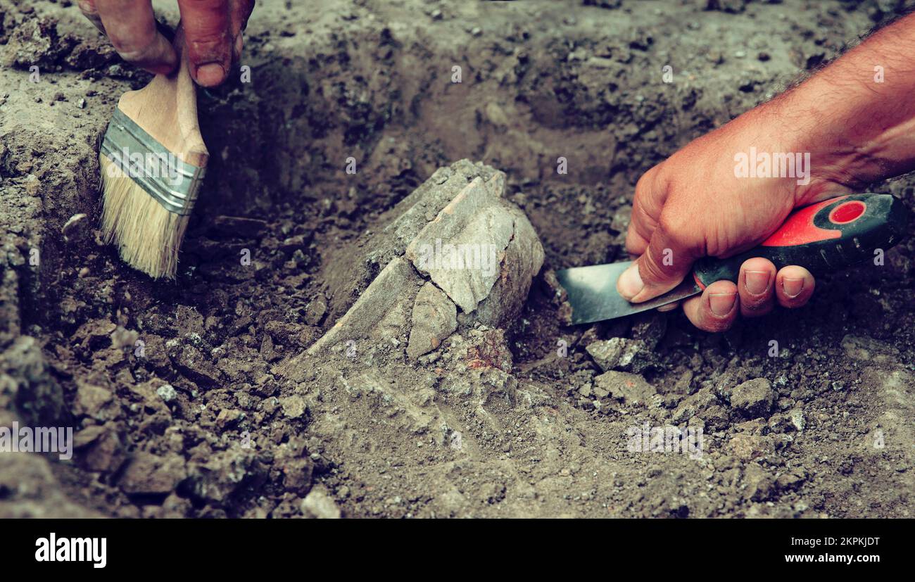 Scavi archeologici, archeologi lavorano, scavare un antico manufatto di argilla con attrezzi speciali nel terreno Foto Stock