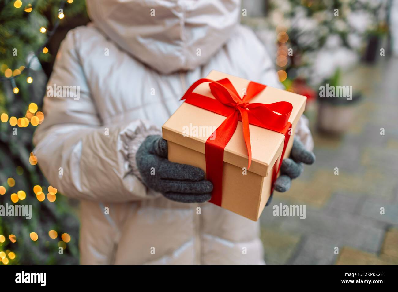 Primo piano delle mani dare a sorpresa scatola regalo, regalo marrone scatola pacchetto con nastro rosso. Festa compleanno concetto Natale banner panoramico Foto Stock