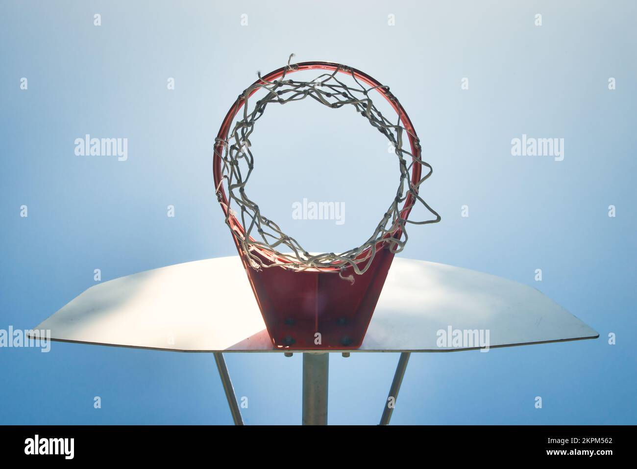 Vista ad angolo basso di un canestro da basket, di una rete e di una tavola posteriore contro un cielo blu Foto Stock