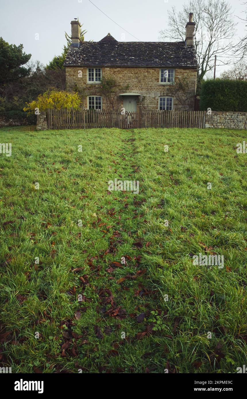 Cottage in pietra Cotswold con un percorso in erba a Wyck Rissington, Gloucestershire, Regno Unito Foto Stock