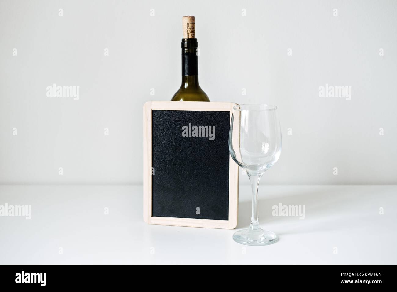 Bottiglia di vino, bicchiere e mockup vuoto. Bottiglia di vino con bicchiere vuoto e lavagna mockup sul tavolo. Foto Stock