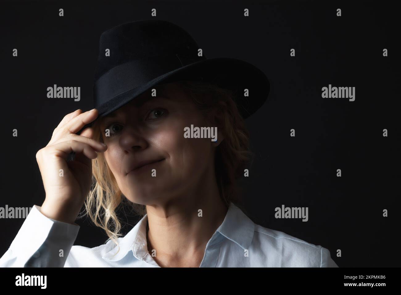 Basso ritratto chiave di donna sorridente di mezza età con cappello nero. Foto Stock