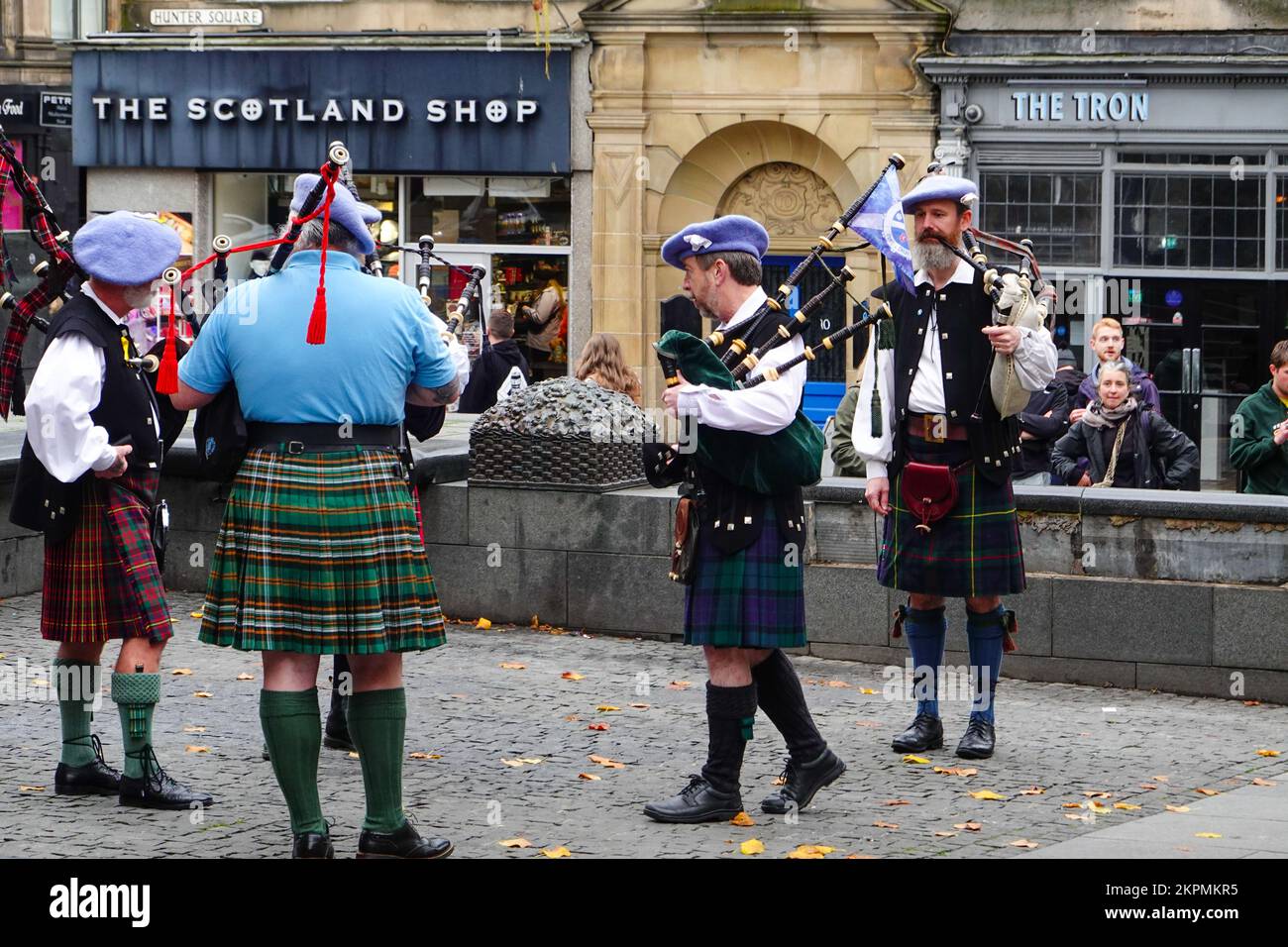 Gli spettatori che osservano i bagpiper in kilt tradizionali che si preparano ad esibirsi, in Hunter Square, appena fuori dal Royal Mile, Edimburgo, Scozia, Regno Unito. Foto Stock