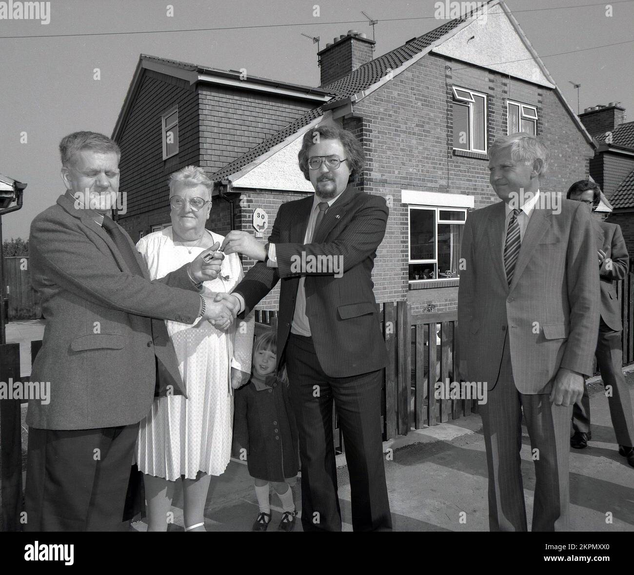1980s, storico, in piedi fuori per una foto, una coppia matura che è data la chiave alla loro nuova casa, Inghilterra, Regno Unito. Foto Stock