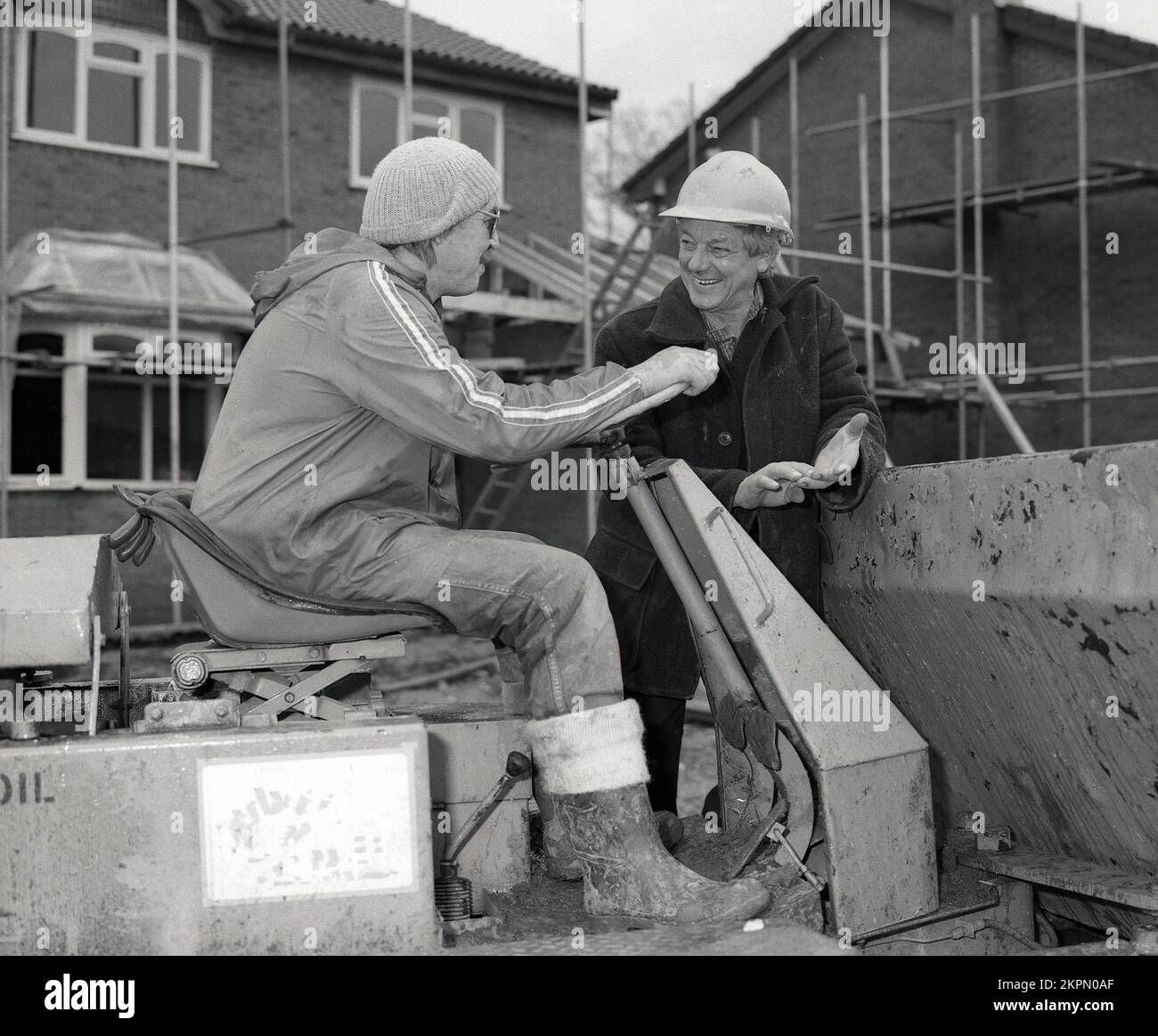 1980s, due costruttori in cantiere, in chat, uno seduto su un carrello di carico pesante, Inghilterra, Regno Unito. vuoi spostare un salto?? Foto Stock