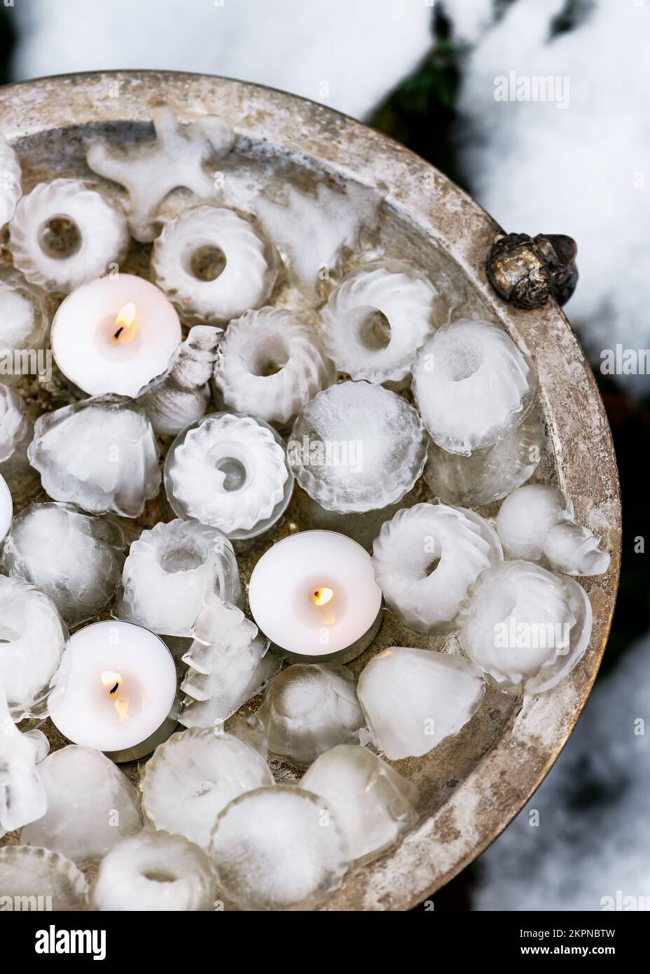 Decorazione artigianale giardino ghiaccio a forma di mini bundt, alberi di Natale, pupazzo di neve con luci del tè brucianti candele su piatto rustico di metallo. Foto Stock