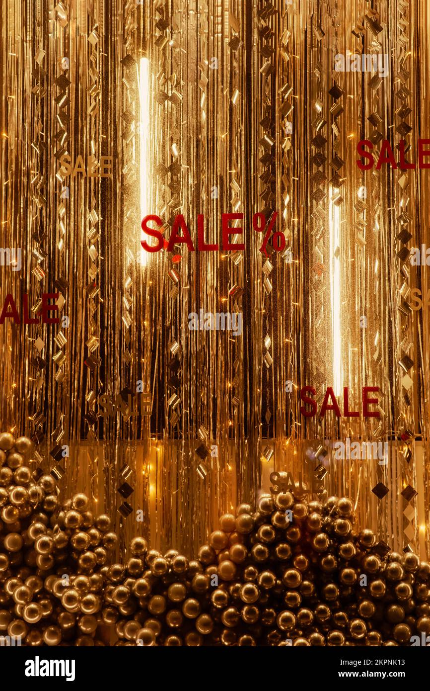 Installazione con palle di Natale e la vendita iscrizione in vetrina dal lato della strada, in serata arredamento d'oro, vetrina festive decorati Foto Stock
