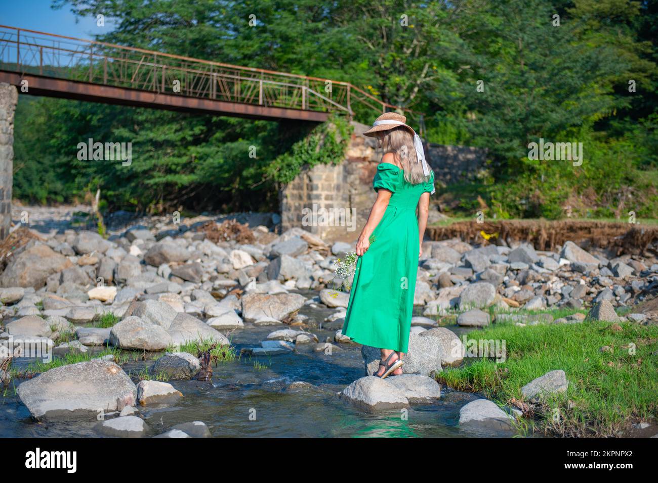 una ragazza in un vestito verde è in piedi presso il fiume Foto Stock