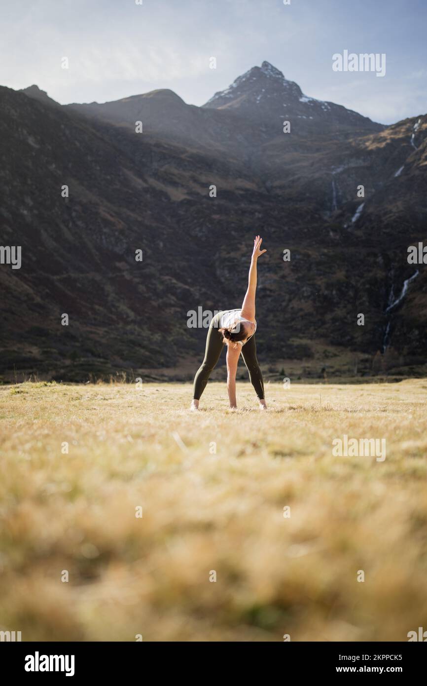 Donna che fa yoga triangolo posa in un prato alpino, Gastein, Austria Foto Stock