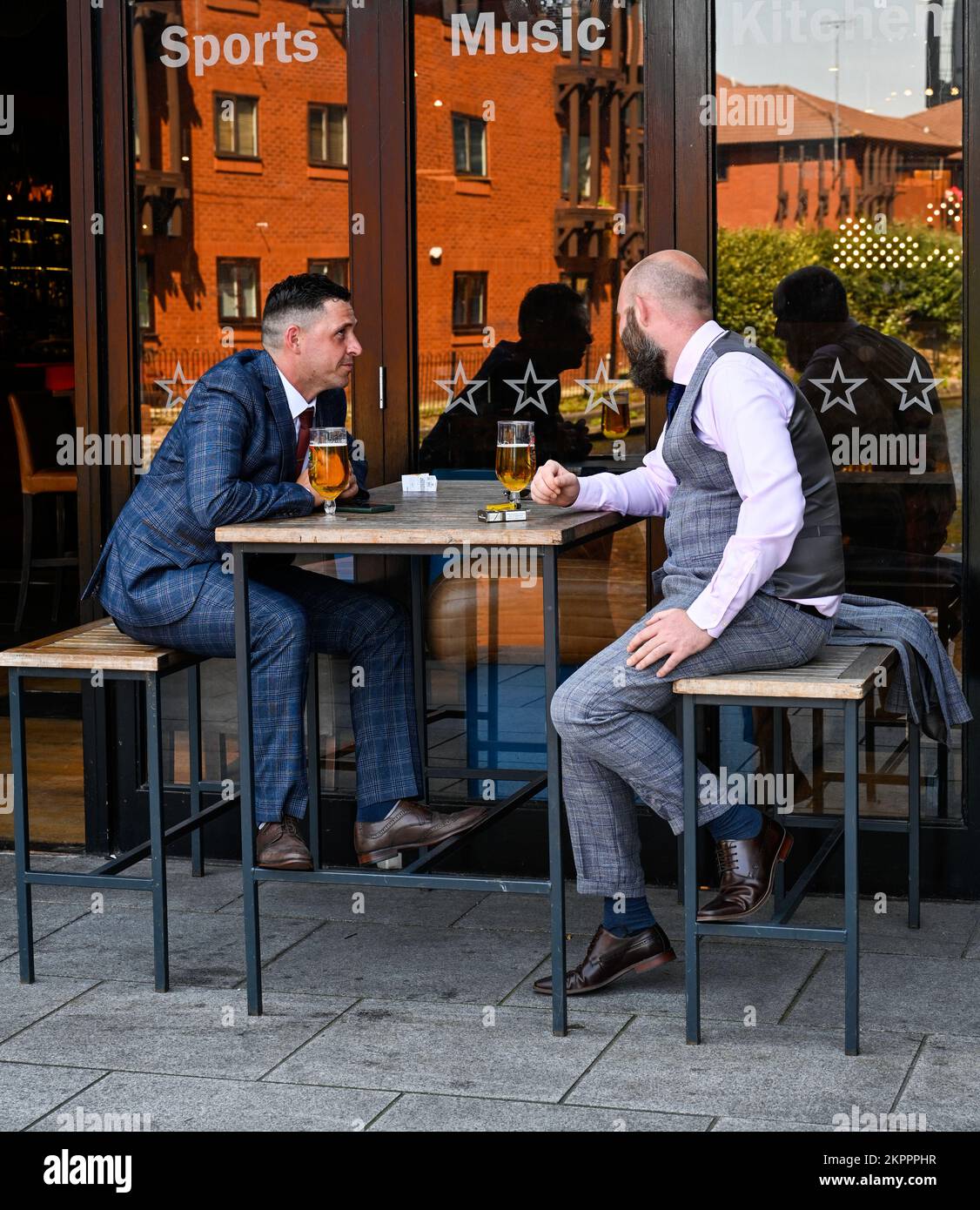 Due uomini in tute d'affari che si gustano un drink a Birmingham, Regno Unito, accanto al canale Foto Stock