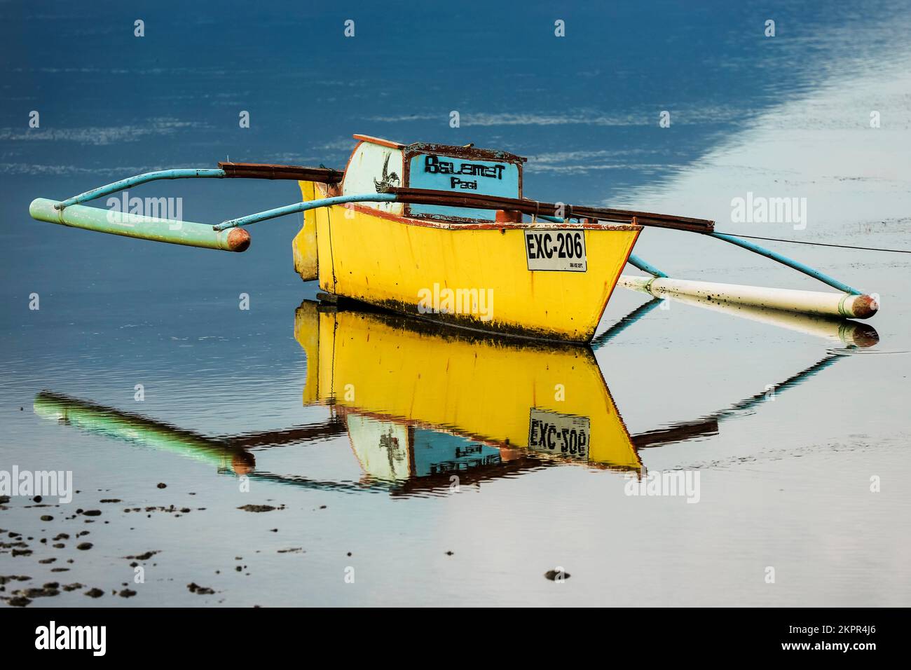 Outrigger barca da pesca riflessa sulla spiaggia di Balirangeng con bassa marea, a sud-est dell'isola di Siau. Siau, Arcipelago di Sangihe, Nord Sulawesi, Indonesia Foto Stock