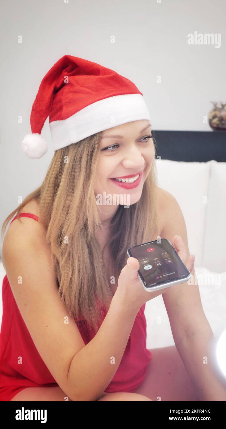 Una donna in un petticoat rosa e un cappello di Natale sta parlando al telefono Foto Stock