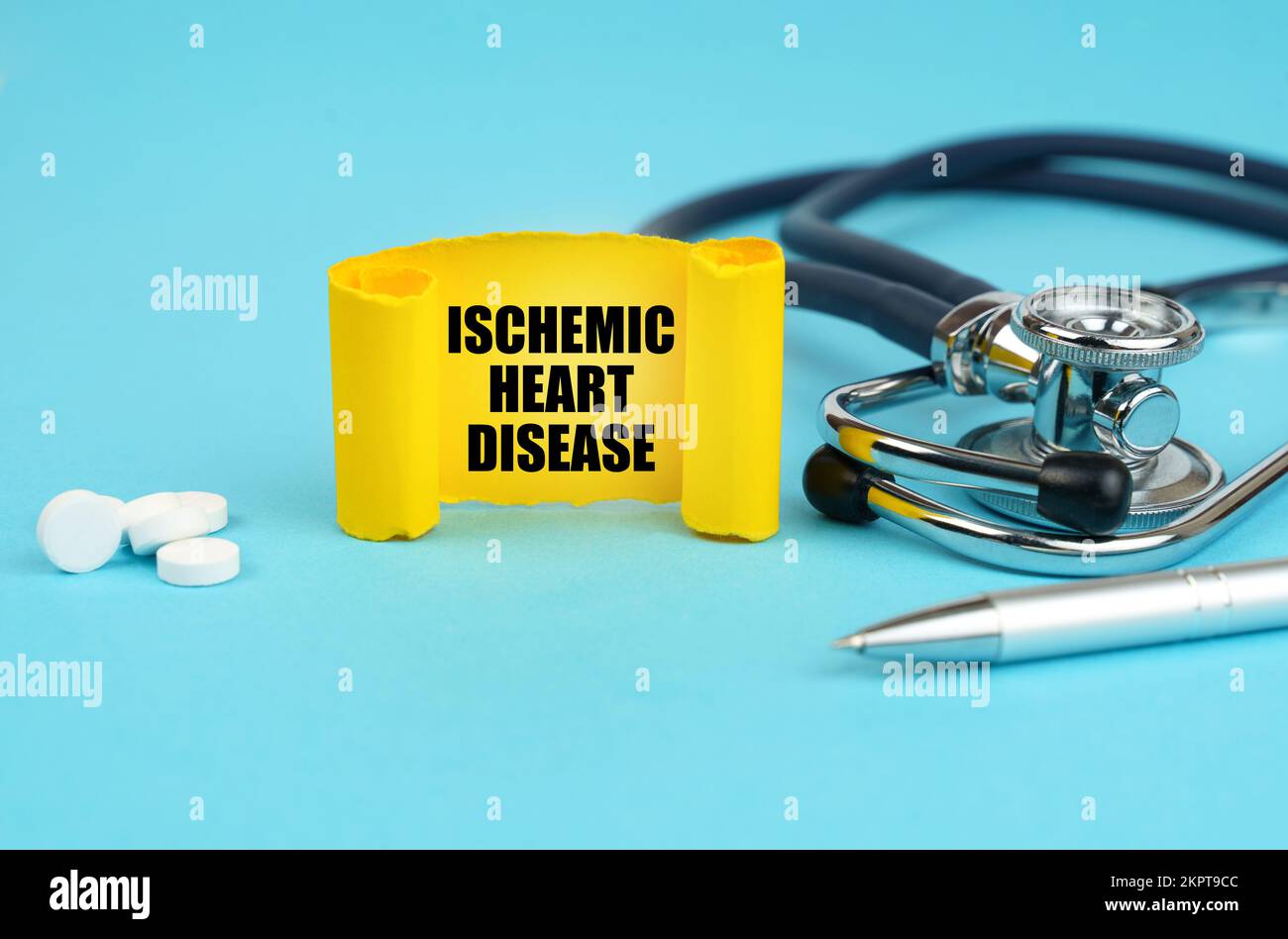 Concetto medico. Su una superficie blu, uno stetoscopio, pillole, una penna e un segno giallo con l'iscrizione - cardiopatia ischemica Foto Stock