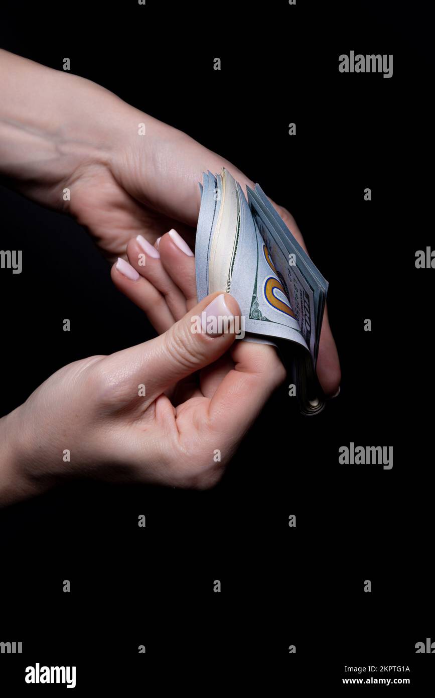 due mani con dollari. Closeup femmina mano dando soldi per qualcosa con isolato su sfondo nero, contare, pagare, shopping con dollaro, corrotti Foto Stock