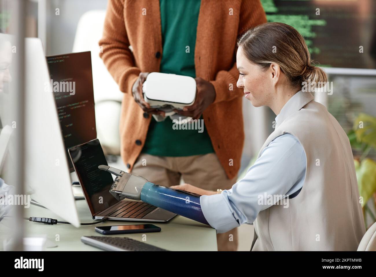 Sorridente sviluppatore di software che indica lo schermo del notebook quando discute delle funzionalità con il project manager Foto Stock