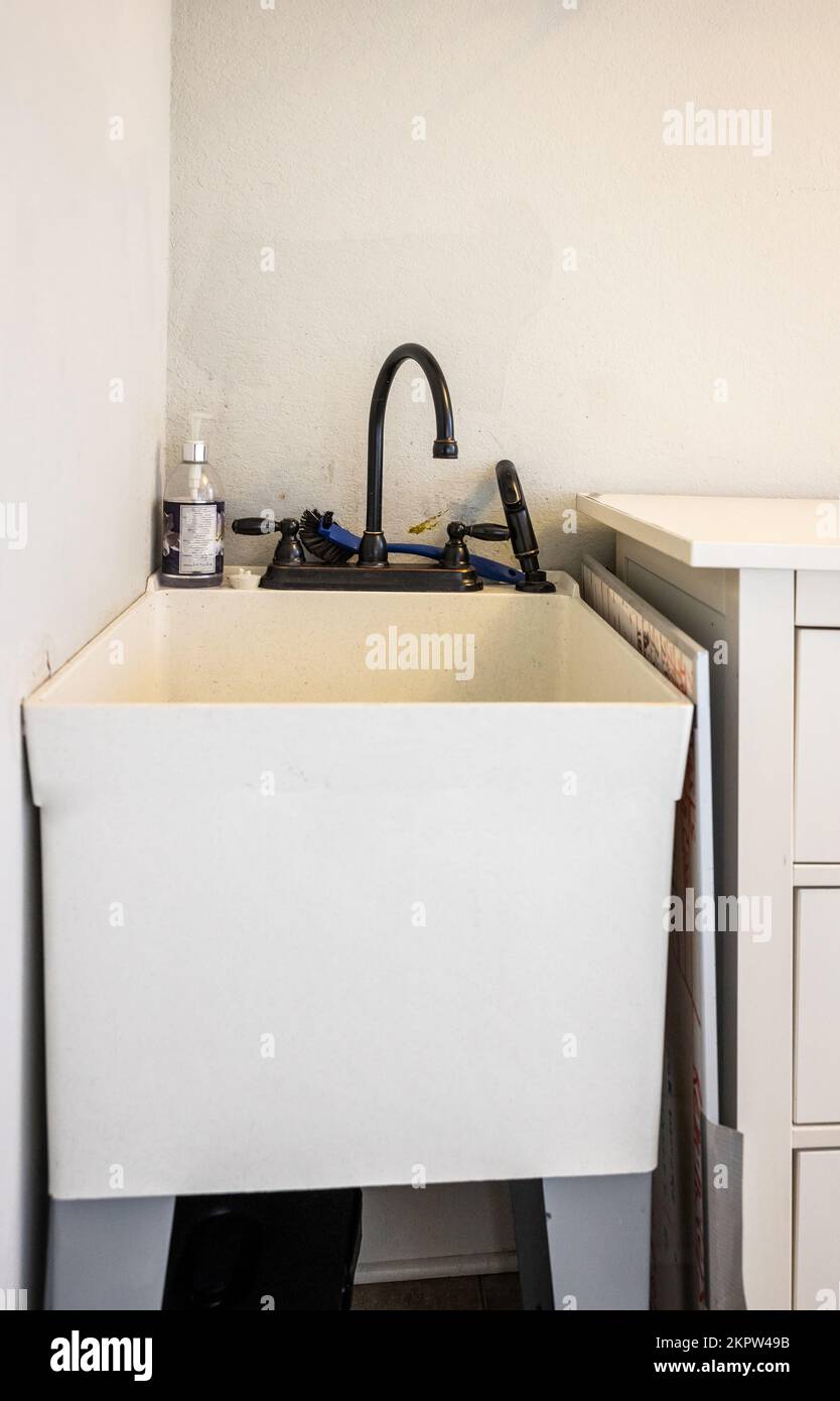 Un piccolo lavabo nell'angolo di una lavanderia di nuova costruzione Foto Stock