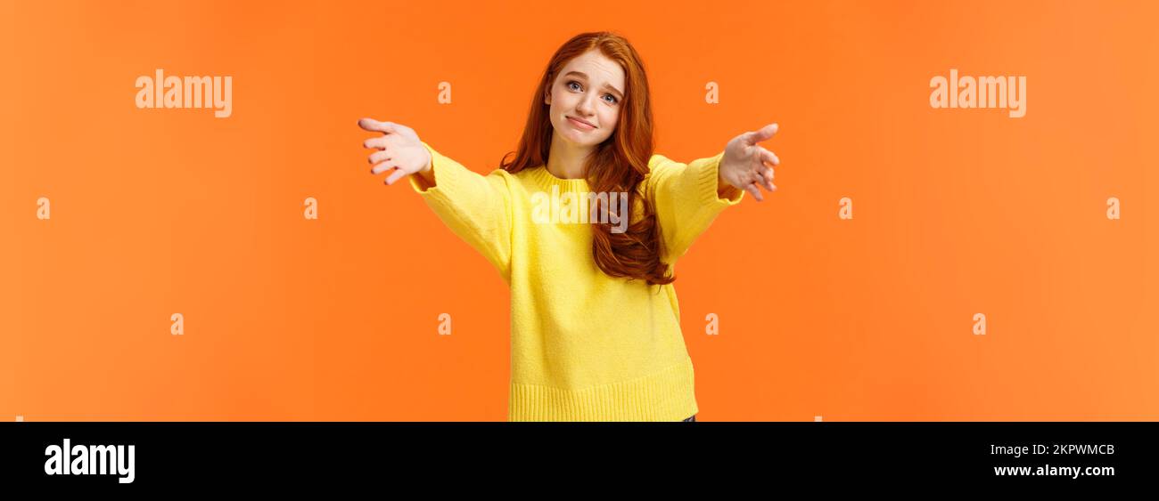 Ragazza chiedendo a venire qui a dare Cheer up abbraccio. Carino e toccò la gara redhead donna in felpa gialla, estendono bracci,allungare le mani avanti per coccolare Foto Stock