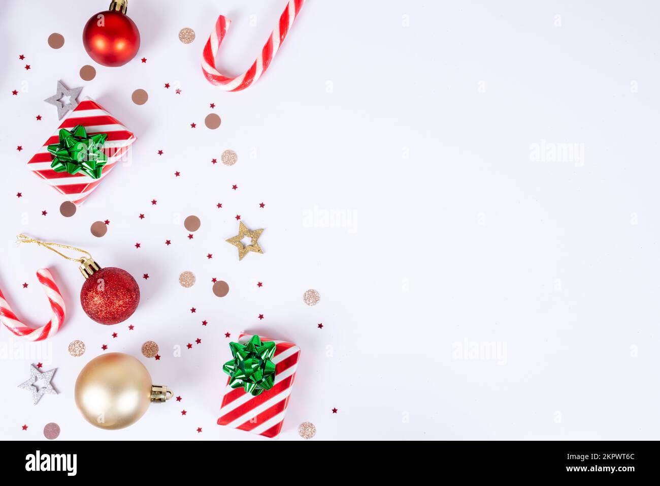 Sfondo di Natale con spazio copia su sfondi bianchi, elementi decorativi con canne caramelle, scatole regalo a righe rosse e bianche e archi verdi, rosso Foto Stock