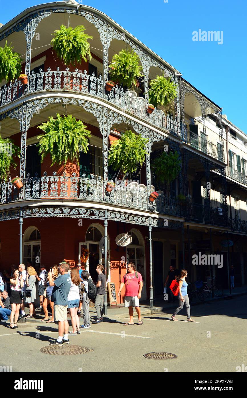 Turisti mulino intorno al quartiere francese di New Orleans in una giornata di sole con felci appesi dai balconi e gallerie Foto Stock