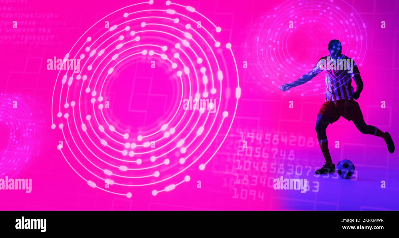 Giocatore di calcio maschile afro-americano che calcia la palla sopra i cerchi illuminati e la lingua del computer Foto Stock