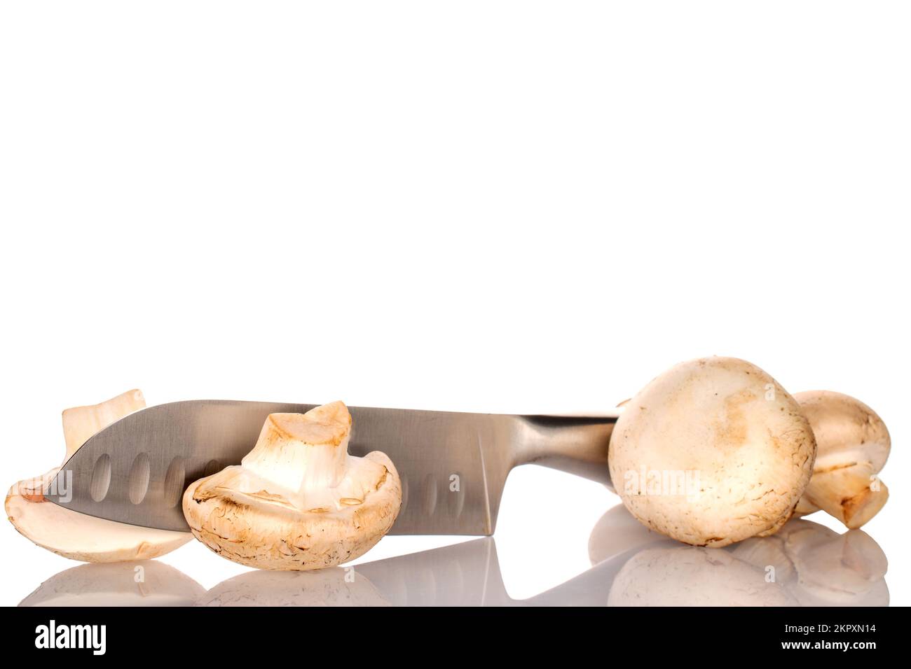 Due interi e due metà di funghi appetitosi freschi biologici champignon con coltello metallico, primo piano, su fondo bianco. Foto Stock