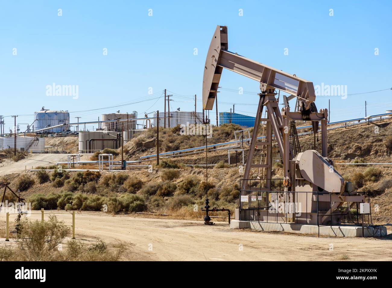 Pozzo di petrolio con condutture e serbatoi in background Foto Stock