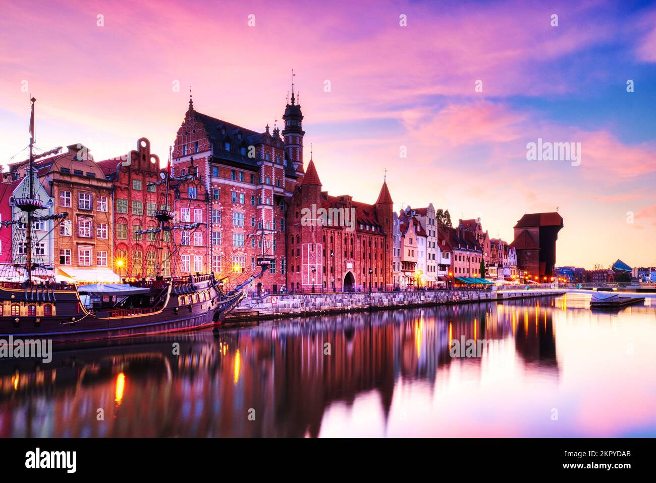 Illuminata la città vecchia di Danzica con il tranquillo fiume Motlawa al tramonto, Polonia, Europa Foto Stock
