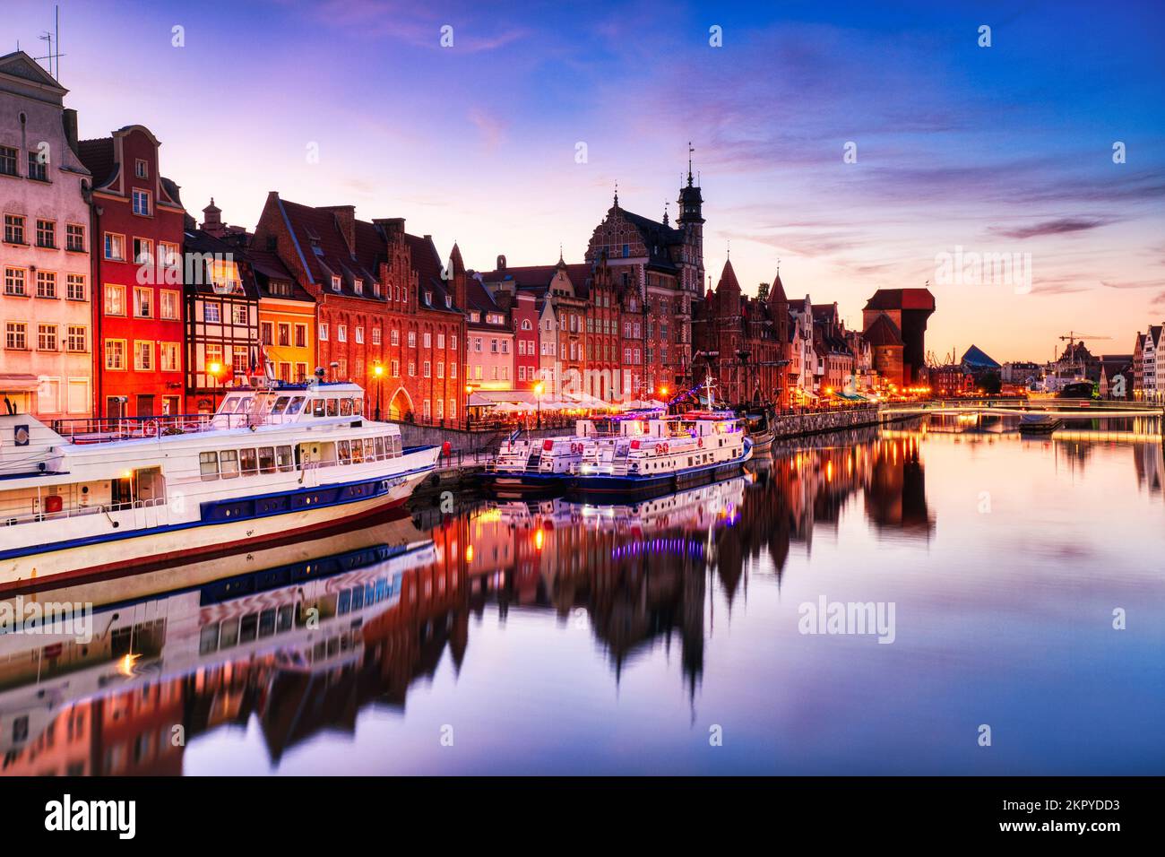 Illuminata la città vecchia di Danzica con il tranquillo fiume Motlawa al tramonto, Polonia, Europa Foto Stock