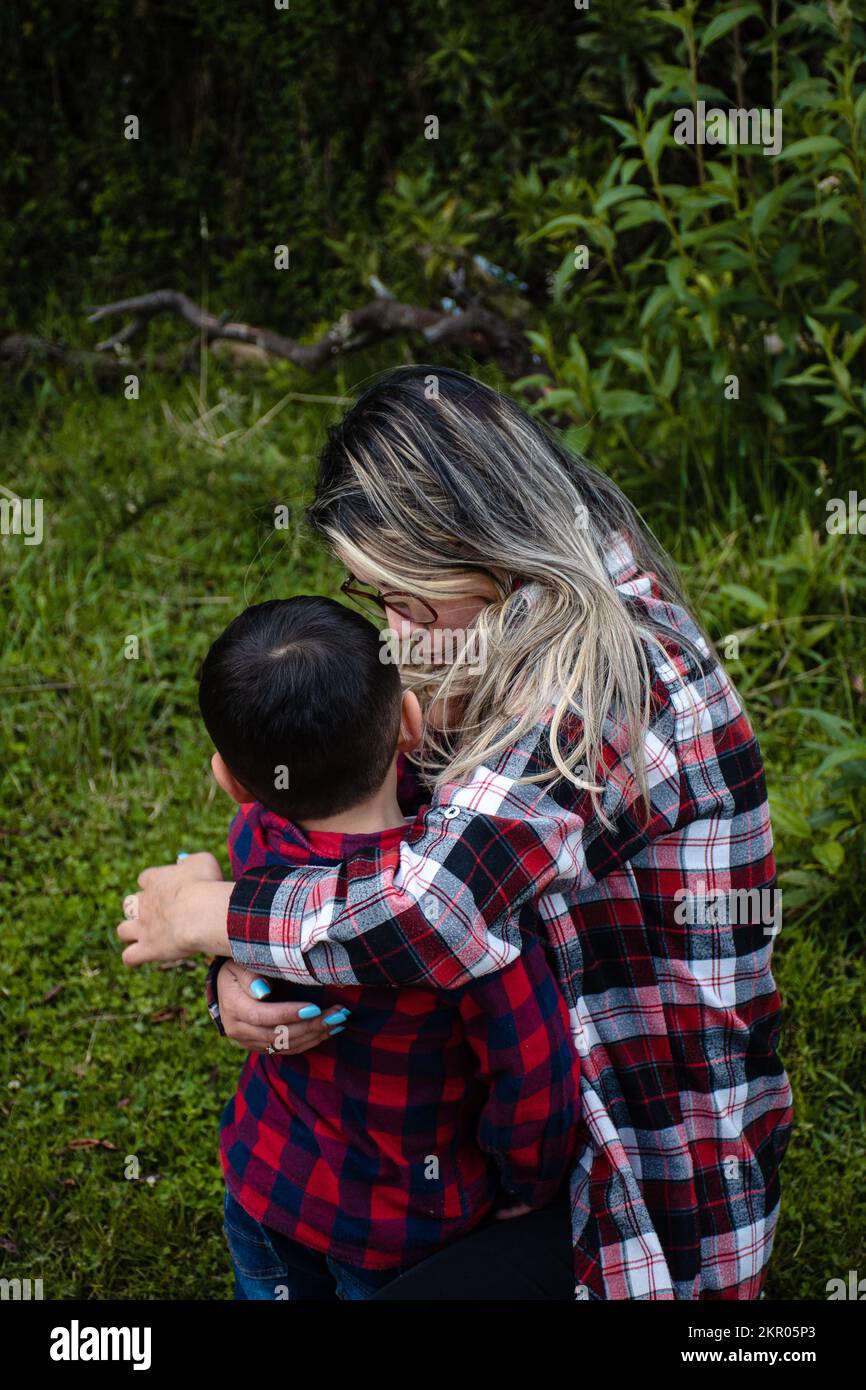 mamma confortando suo figlio in camicie a plaid Foto Stock