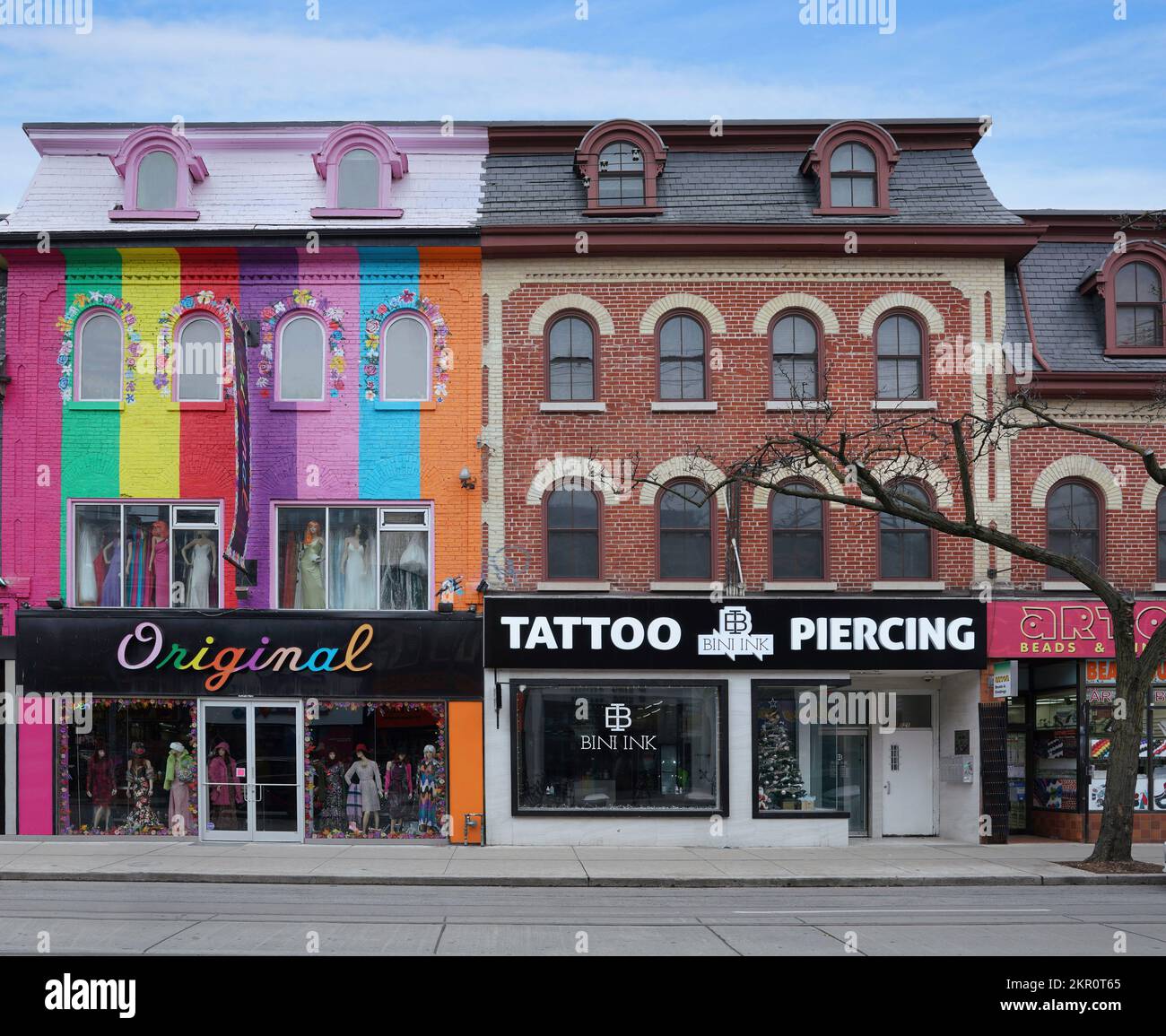 Toronto, Canada - Novembre 2022: Negozi colorati su Queen Street West, un quartiere alla moda, in edifici del 19th ° secolo con tetto mansarda e dormitorio Foto Stock
