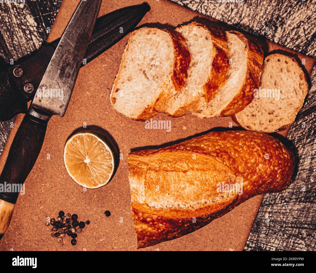 pane su tavola con coltello sparato in testa, sfondo nero rustico Foto Stock