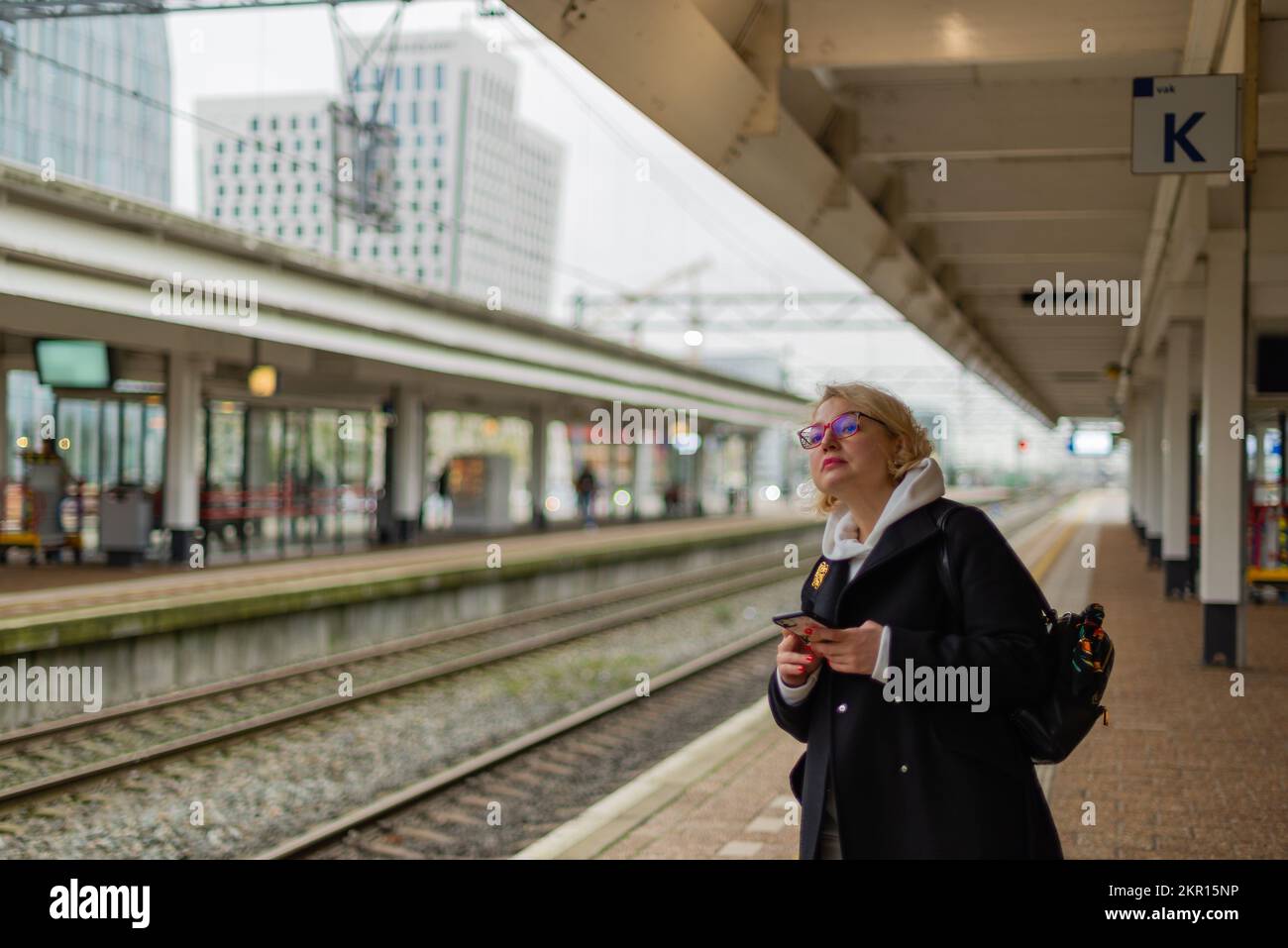 Donna sulla piattaforma della stazione di rialway che cerca il treno Foto Stock