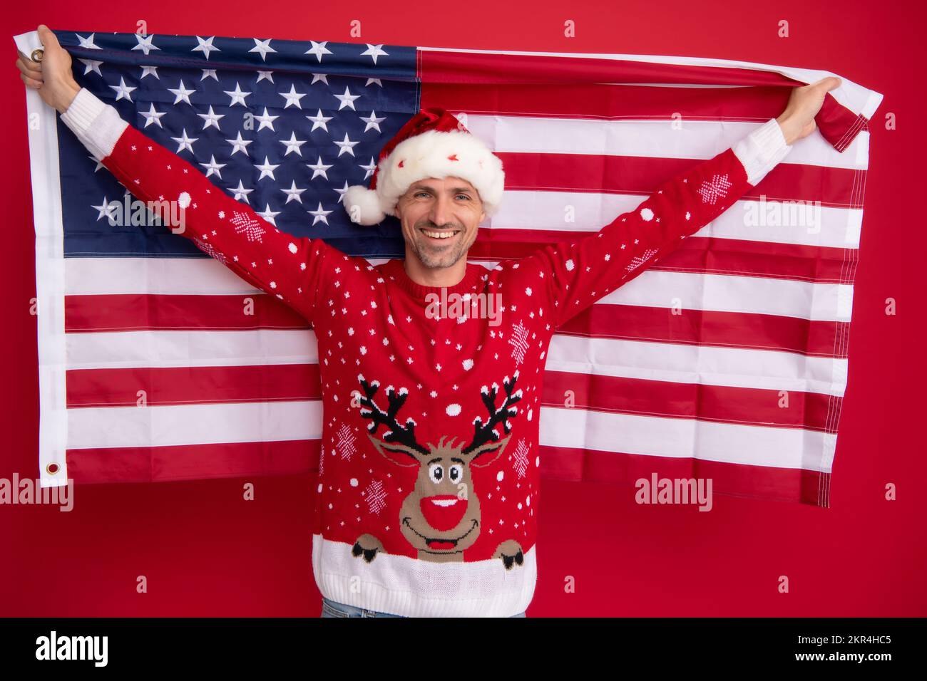 Santa Hold bandiera americana. Natale negli stati uniti, usa. santa di  mezza età. Uomo a Natale maglione invernale su sfondo rosso Foto stock -  Alamy
