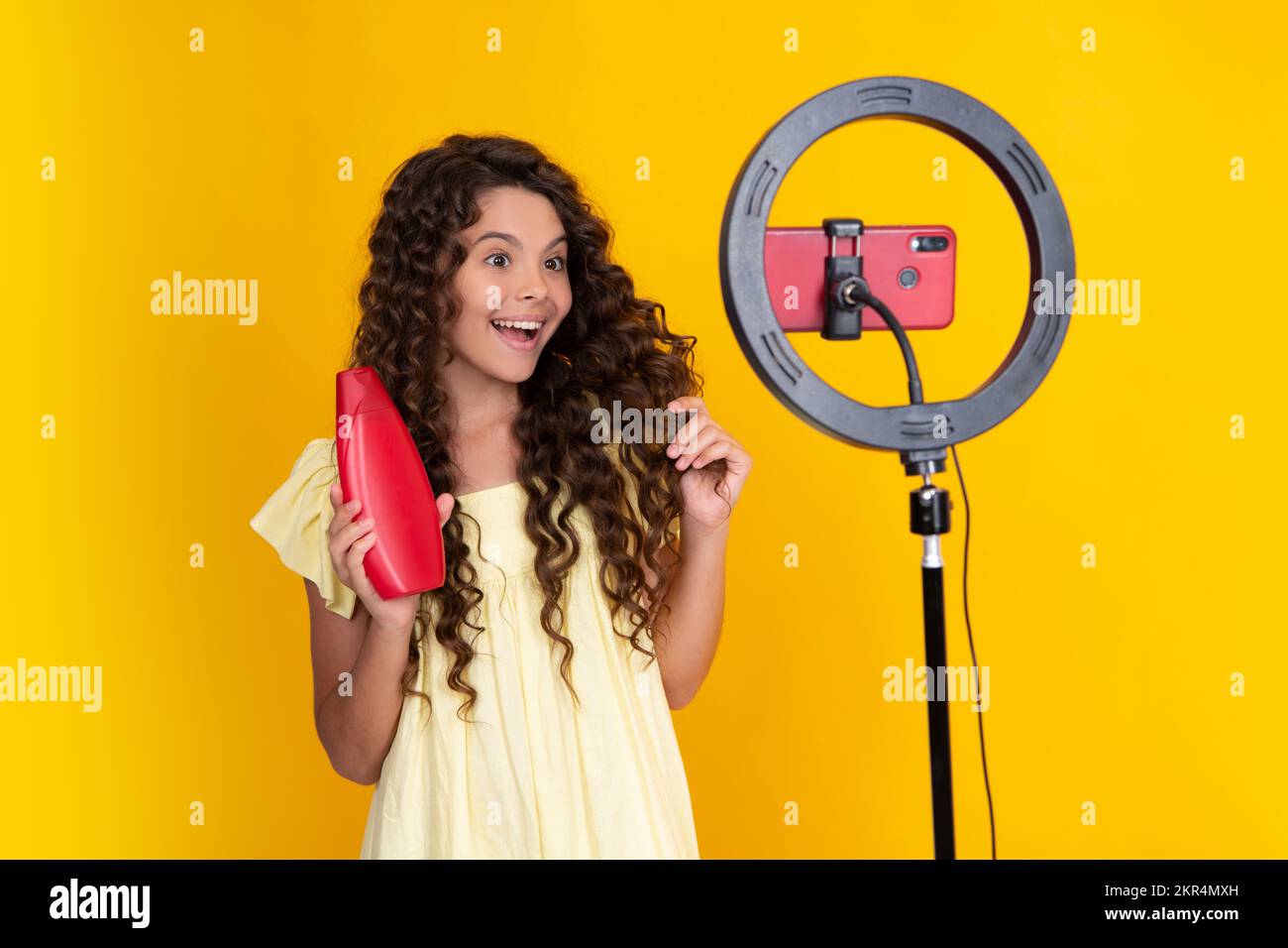 Teenager blogger tenere balsamo per capelli o bottiglia shampoo fare video, bambino vlogger influencer record contenuto. Foto Stock