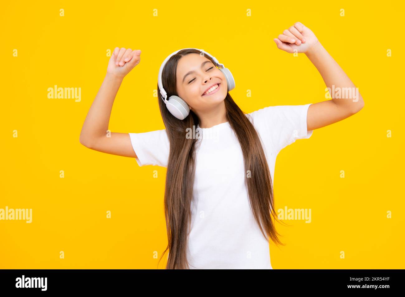 Teen girl in cuffie ascoltare musica. Dispositivo auricolare wireless. I bambini amano la musica in auricolari su sfondo giallo. Foto Stock