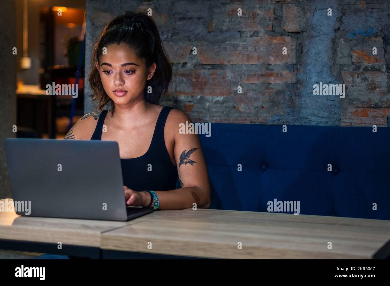 Nomade digitale femminile che lavora su un computer portatile in uno spazio di coworking contemporaneo Foto Stock