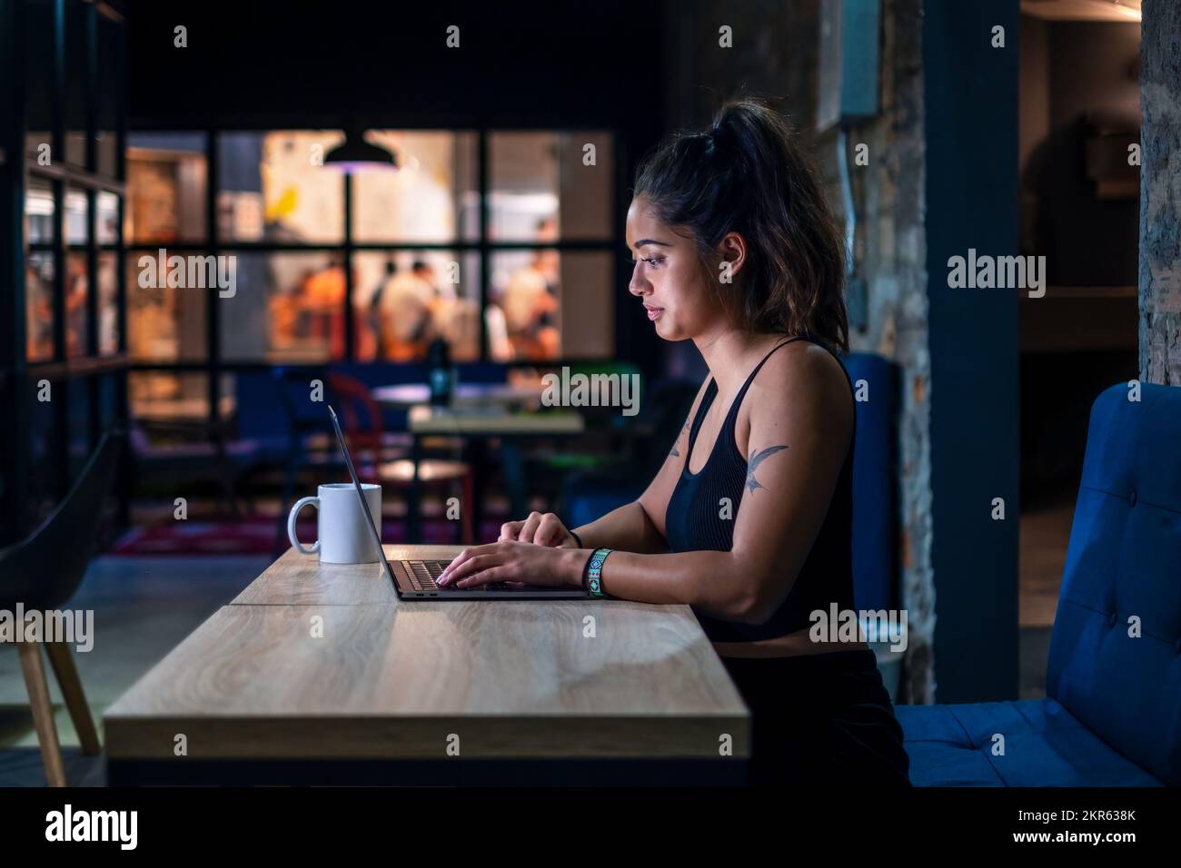 Nomade digitale femminile che lavora su un computer portatile in uno spazio di coworking contemporaneo Foto Stock