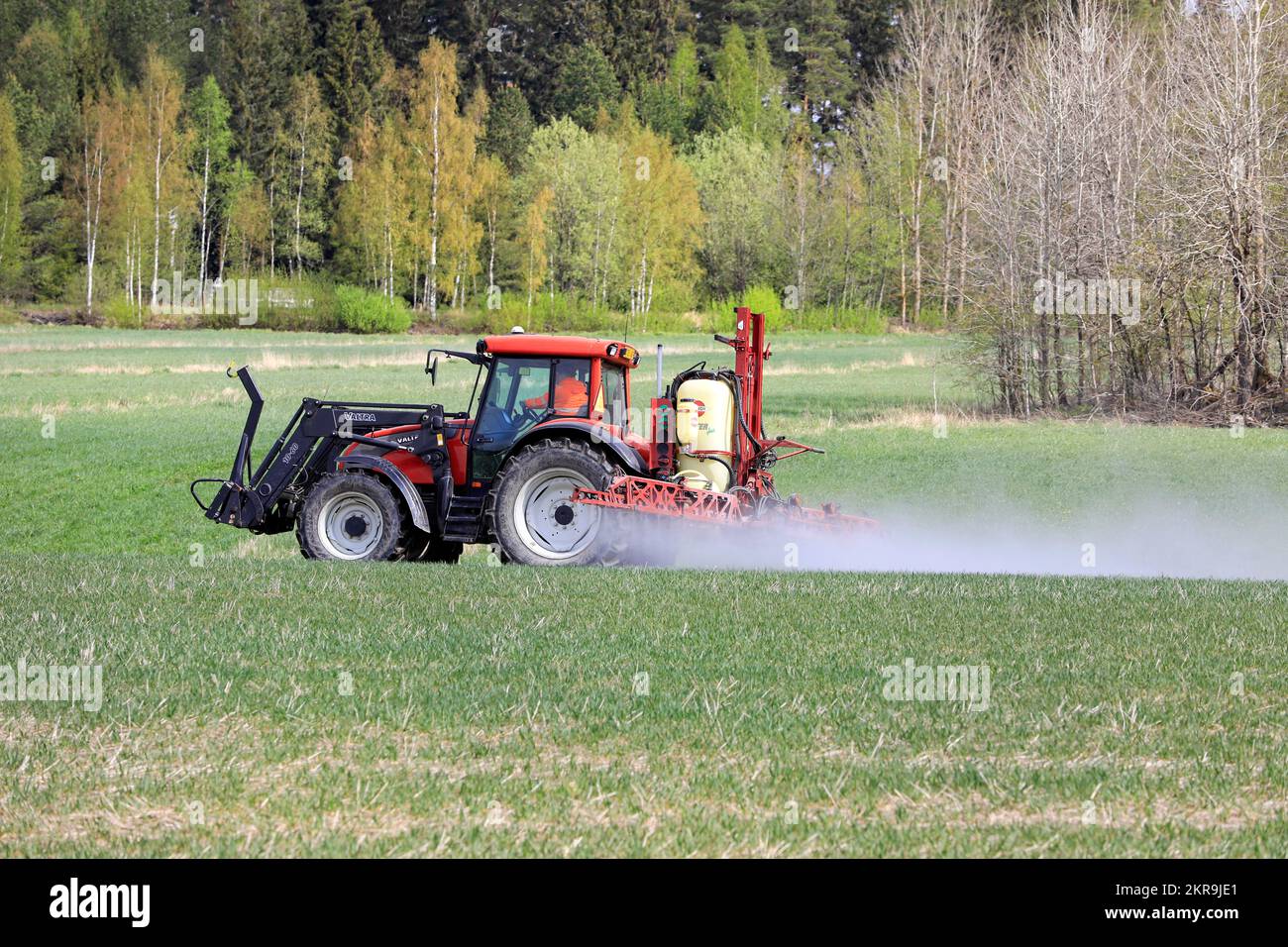 Un giorno di primavera irrorando il campo con il trattore Valtra e l'irroratrice con sollevatore Hardi Master Plus. Salo, Finlandia. 16 maggio 2021. Foto Stock