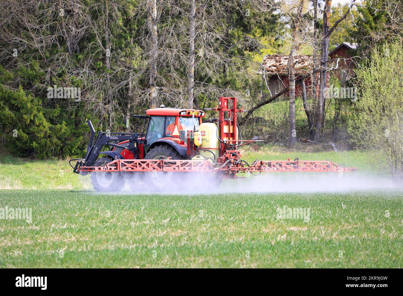 Un giorno di primavera irrorando il campo con il trattore Valtra e l'irroratrice con sollevatore Hardi Master Plus. Salo, Finlandia. 16 maggio 2021. Foto Stock