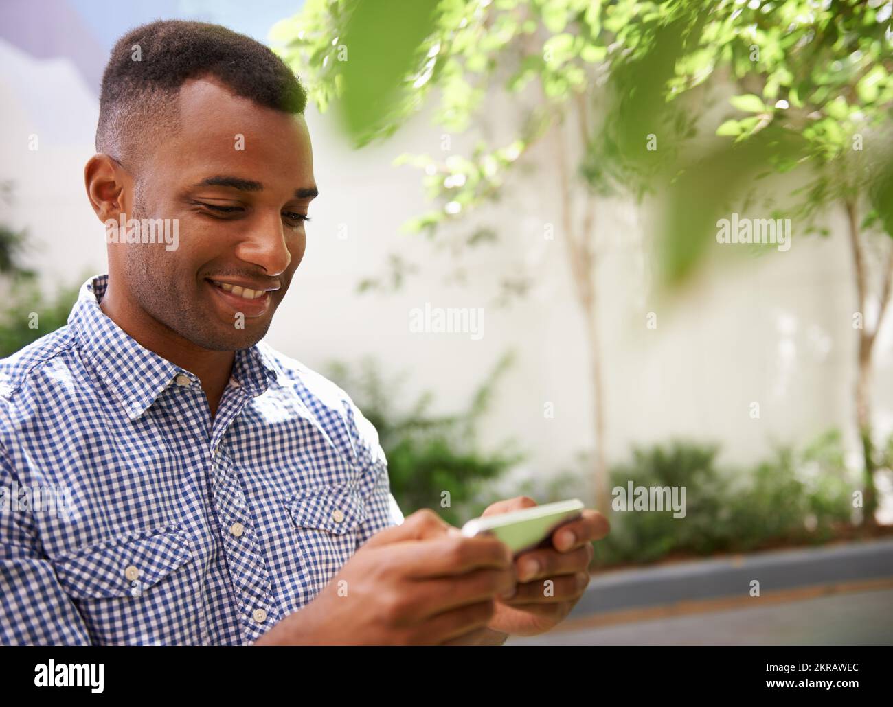 Comunicazione intelligente e scattante. un giovane uomo di etnia che usa il suo dispositivo wireless all'esterno. Foto Stock