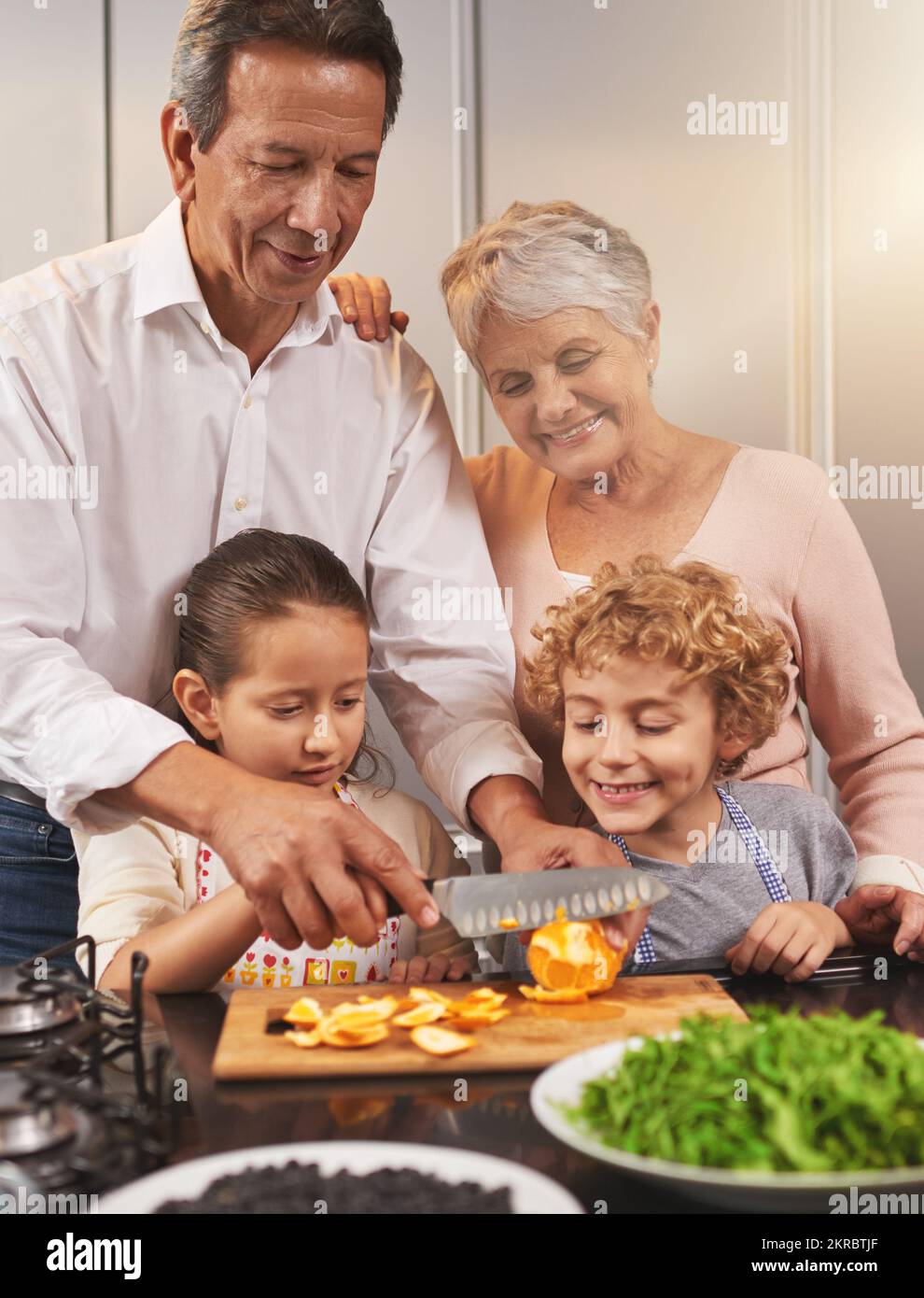 Granny e nonni piccoli aiutanti. Un fratello e una sorella che aiutano a fare la cena a casa dei loro nonni. Foto Stock