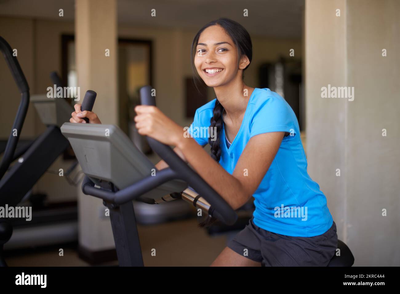 Allenamento completo del corpo. Giovane donna etnica che lavora in palestra su una cyclette. Foto Stock