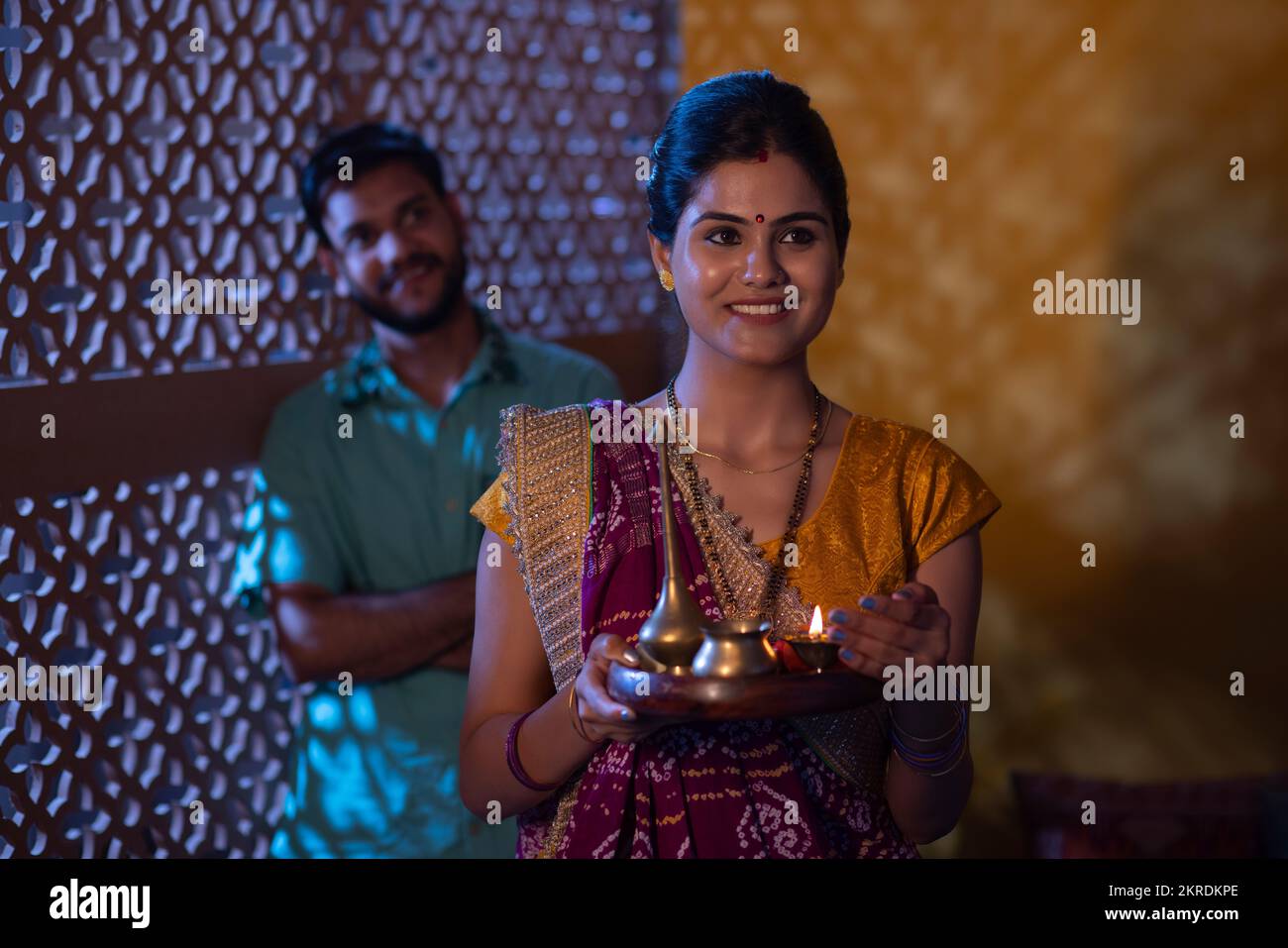 Gujrati donna in piedi con puja thali e suo marito in piedi dietro Foto Stock