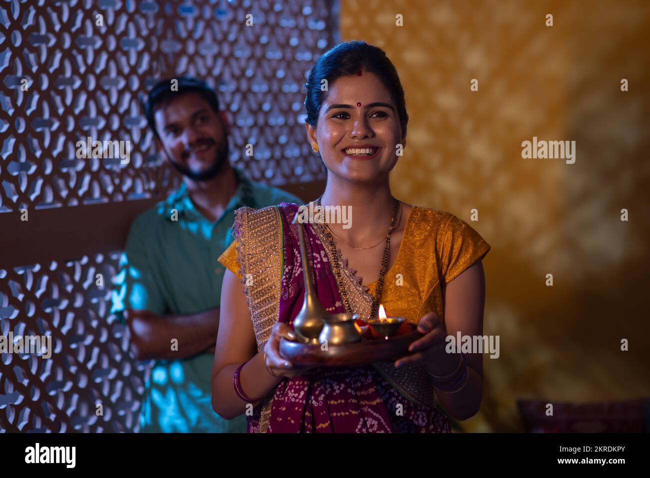 Gujrati donna in piedi con puja thali e suo marito in piedi dietro Foto Stock